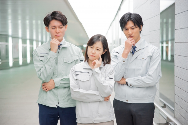 真剣な表情の3人の作業着の人々